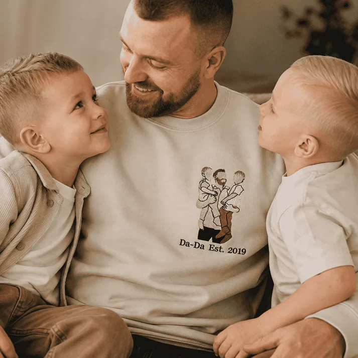 Pai sorrindo com dois filhos usando moletom bordado Da-Da Est. 2019